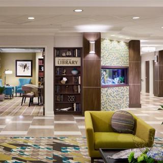 A modern hotel lobby featuring stylish furniture, a library section, and elegant decor.