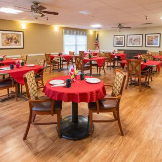 A neatly arranged dining area featuring tables with red tablecloths and wooden chairs.