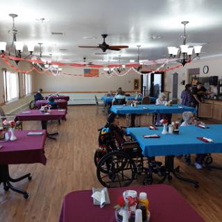 A spacious dining area with colorful tables, suitable for gatherings in a care facility.