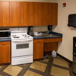 A small kitchen space with a stove, microwave, and wooden cabinets.