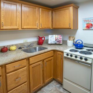 A compact kitchen with wooden cabinets, a stove, and a sink.