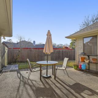 A sunny backyard patio with a table and chairs under an umbrella.