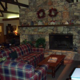 A cozy living room with a stone fireplace and plaid sofa, featuring cabin-style decor.