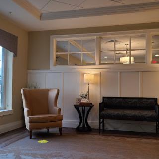 A cozy living room with an armchair, sofa, and warm lighting.