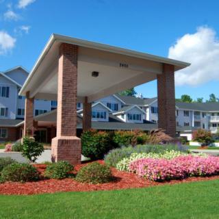 A well-kept residential building with a landscaped entrance featuring colorful flowers.