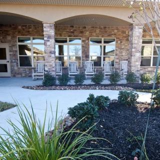 A welcoming porch with rocking chairs outside a stone building.