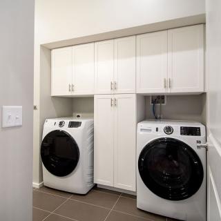 A modern laundry room with a washing machine, dryer, and ample cabinetry.