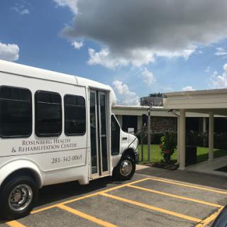 A white transportation bus parked outside a building under a partly cloudy sky.