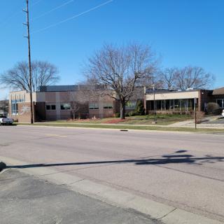 A clear view of a modern building surrounded by trees on a sunny day.
