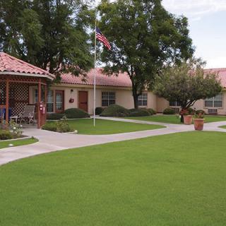 A peaceful residential area with a well-maintained lawn, pathway, and gazebo.