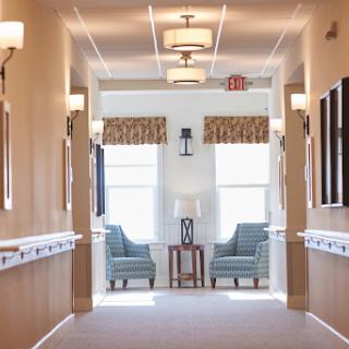 A bright and inviting hallway featuring comfortable seating areas and large windows.