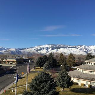 A scenic view of snow-capped mountains behind a residential area under a clear blue sky.