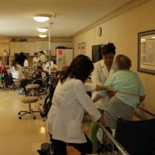 Healthcare workers assisting elderly patients in a nursing home setting.