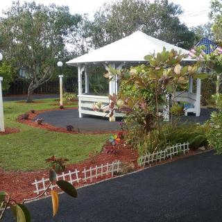 A well-maintained garden featuring a gazebo surrounded by plants and a paved path.