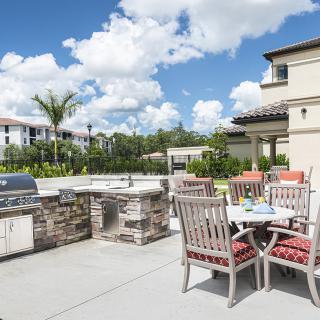 A spacious outdoor patio with a barbecue grill and dining area set against a sunny backdrop.