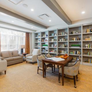 A modern library with bookshelves, a seating area, and a table with chairs.