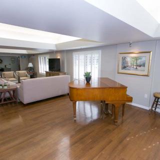 A spacious living room featuring a grand piano, comfortable seating, and elegant decor.