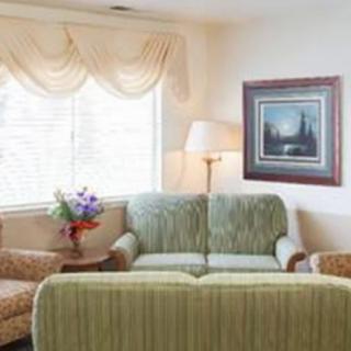 A cozy living room with a sofa, armchairs, a floor lamp, and a painting on the wall.