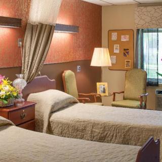 A cozy hospital room with two beds, a bouquet of flowers on the side table, and comfortable seating.