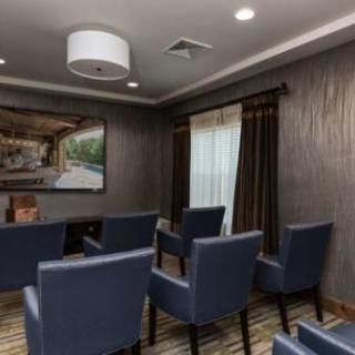 A small, well-furnished meeting room with blue chairs and a large painting on the wall.
