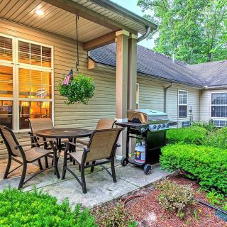 Cozy patio area with seating and a grill, surrounded by lush greenery.