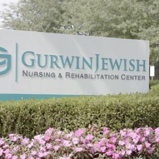 Entrance sign of the Gurwin Jewish Nursing & Rehabilitation Center surrounded by flowers.