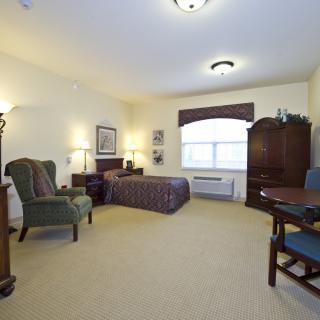 A cozy bedroom with a bed, armchair, and wooden furniture.