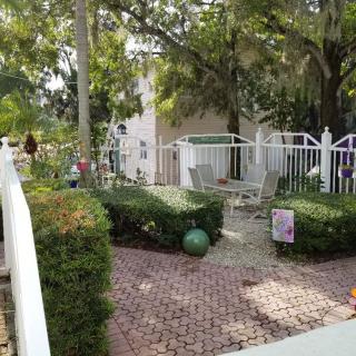 A peaceful garden setting with a fenced patio and surrounded by tall trees.