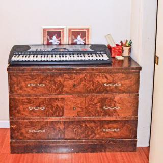 A wooden dresser topped with a keyboard, two framed photos, and pencils in a holder.