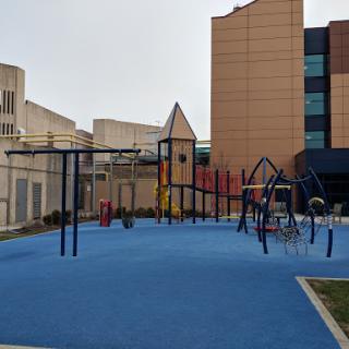 A playground equipped with various play structures set against a modern urban backdrop.