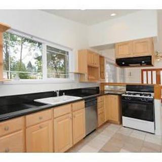Modern kitchen with wooden cabinets and black countertops.