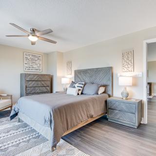 A modern bedroom with a stylish gray bed, matching furniture, and elegant lighting.