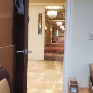 A view of a hotel lobby through an open doorway, featuring elegant chandeliers and polished floors.