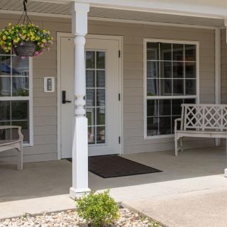A cozy porch with benches, a hanging plant, and a welcoming entrance.