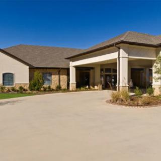 A modern building with a covered entrance and a spacious driveway under a clear blue sky.