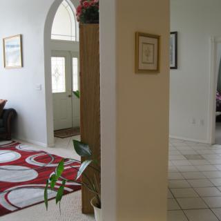 A cozy home interior with a living room and entryway, featuring a red carpet and house plants.