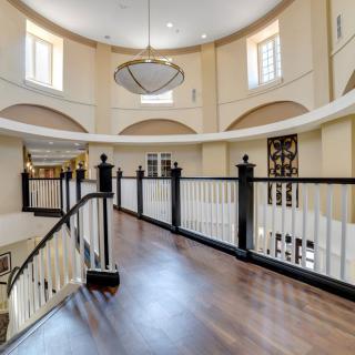 Elegant interior with a wooden floor, curved balcony, and a large chandelier.