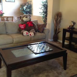 Cozy living room with a large teddy bear on the sofa and a wooden coffee table.
