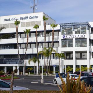 A health center building with signage for Silverado, surrounded by palm trees and a parking lot.