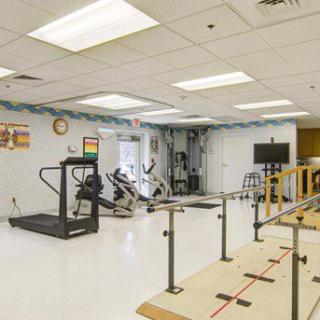 A well-equipped rehabilitation therapy room with exercise machines and parallel bars.