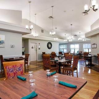 A cozy restaurant dining area with neatly arranged tables and chairs, featuring elegant lighting and decor.