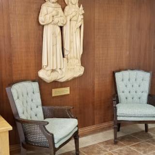 A serene waiting area featuring light blue upholstered chairs and a carved wooden sculpture on the wall.