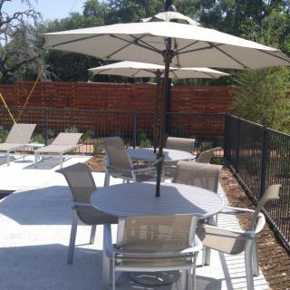 Outdoor patio area with tables, chairs, and umbrellas providing shade.