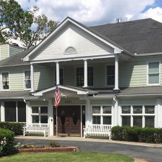 A two-story residential house with a porch and an American flag.
