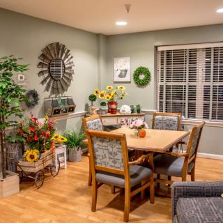 A cozy dining room with a wooden table and chairs, decorated with plants and wall art.