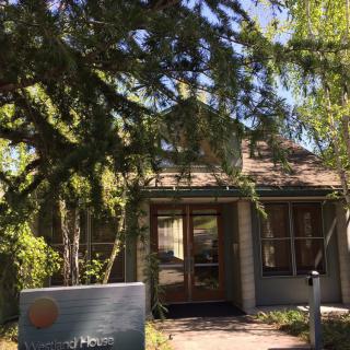 A small building surrounded by trees with a sign out front.