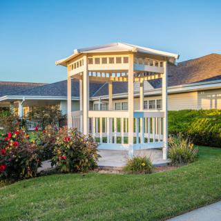A charming gazebo stands amidst a well-maintained garden with vibrant flowers.