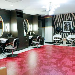 A modern hair salon interior with stylish black and white decor, featuring mirrors, salon chairs, and a zebra-patterned wall.
