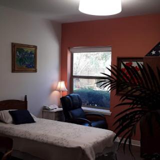 A cozy bedroom featuring a single bed, a comfortable chair by the window, and decorative elements.