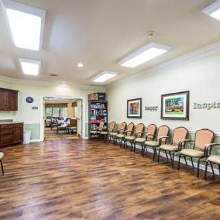 A spacious waiting room with neatly arranged chairs along the wall and bright overhead lighting.